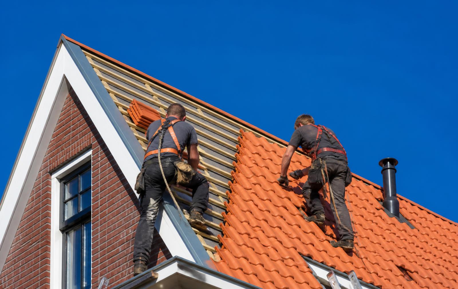 Dakdekkers leggen nieuwe dakpannen op een hellend dak